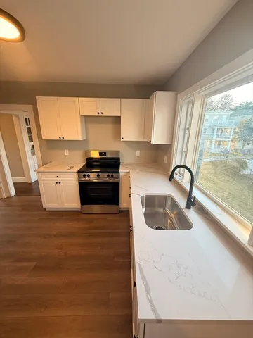 a kitchen with granite countertop a stove a sink and a microwave