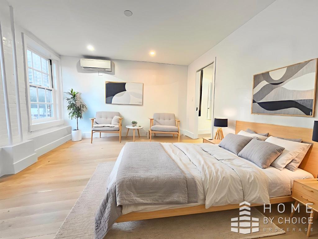 25 Peck Slip, Unit 3 Manhattan, NY 10038 - Photo 9 of 15 a spacious bedroom with a large bed and a chandelier