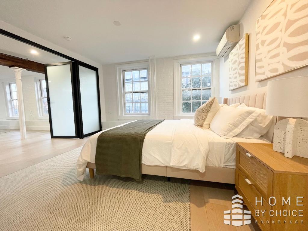 25 Peck Slip, Unit 3 Manhattan, NY 10038 - Photo 10 of 15 a bedroom with a bed and a large window