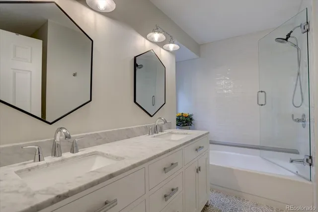 a bathroom with a double vanity sink mirror and bathtub