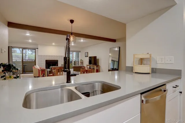 a kitchen with a sink a counter top space and living room view