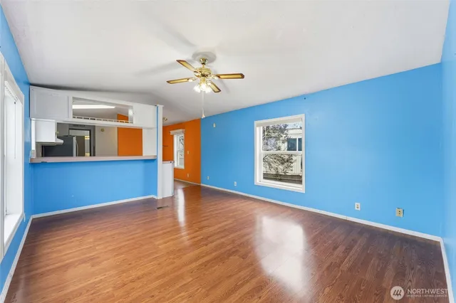 a view of an empty room with window and wooden floor