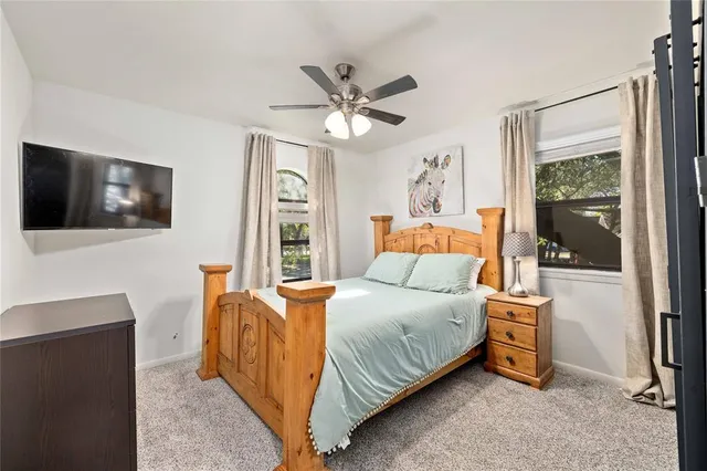 a bedroom with a bed a flat screen tv and a large window