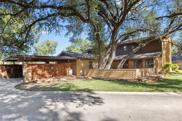 a backyard of a house with large trees and wooden fence