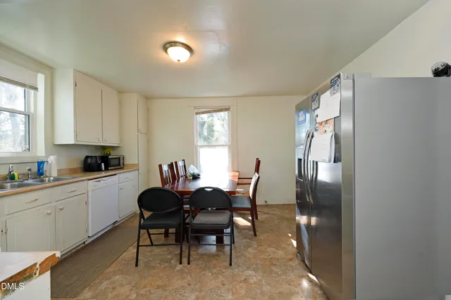 a kitchen with stainless steel appliances a dining table chairs and a refrigerator