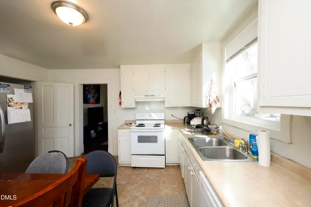 a kitchen that has a lot of cabinets stainless steel appliances and a window