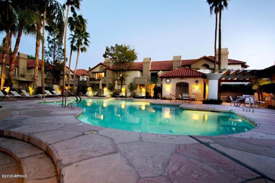a view of swimming pool with a yard and palm trees