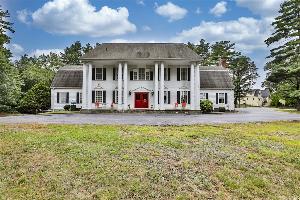 47 Sugar Road Bolton, MA 01740 - Photo 1 of 42 a view of a white house with a large pool and lawn chairs under an umbrella