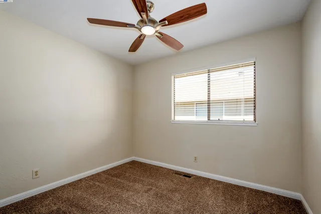 an empty room with a window and a fan