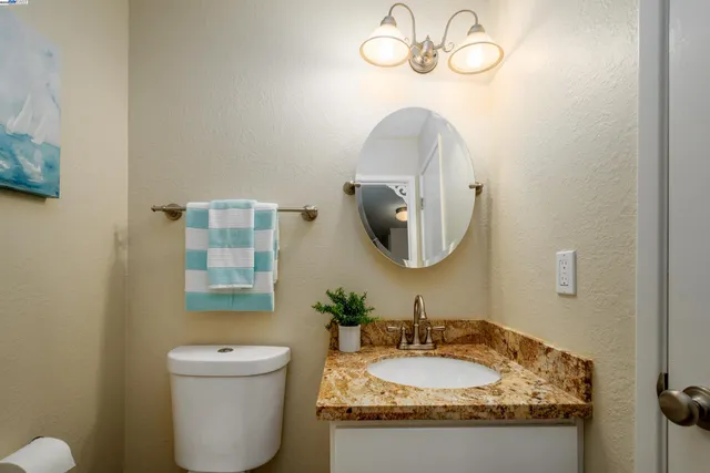 a bathroom with a granite countertop sink a mirror and a toilet