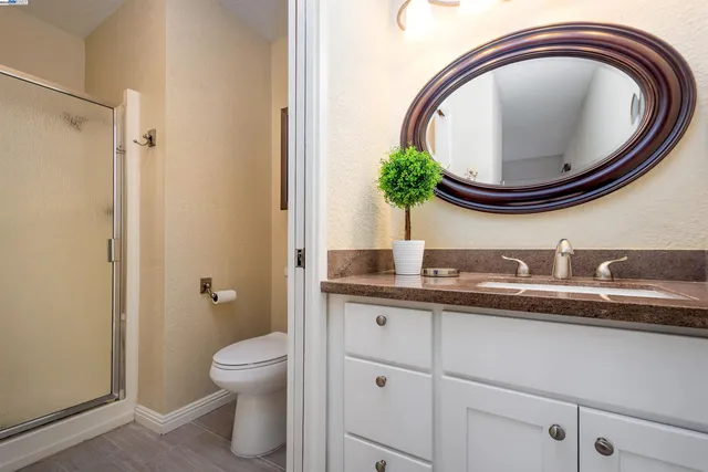 a bathroom with a granite countertop toilet a sink and a mirror
