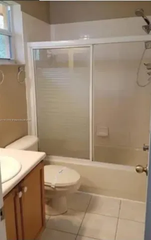 a bathroom with a granite countertop bathtub shower sink vanity and toilet