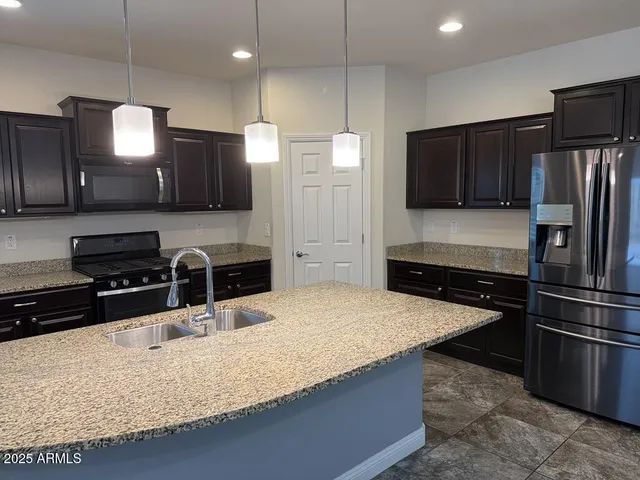 a kitchen with stainless steel appliances kitchen island granite countertop a refrigerator a stove a sink and a refrigerator