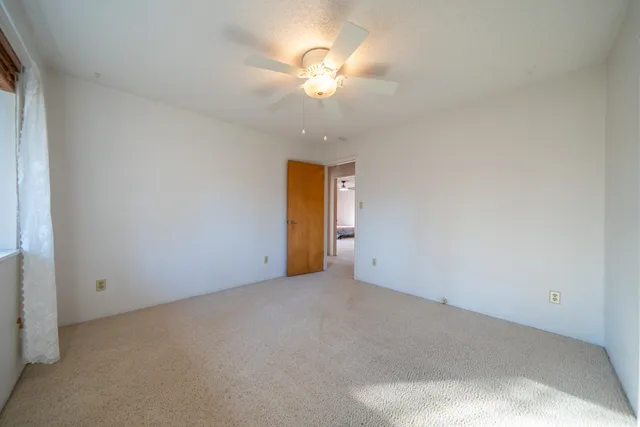 an empty room with a ceiling fan and window
