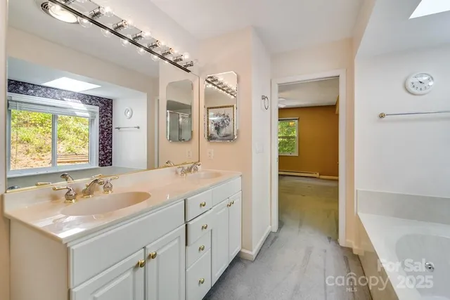 a spacious bathroom with a tub sink and mirror