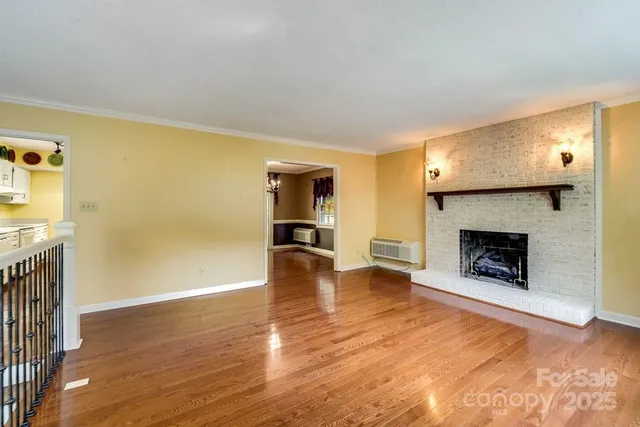 a view of a livingroom with wooden floor a fireplace and window