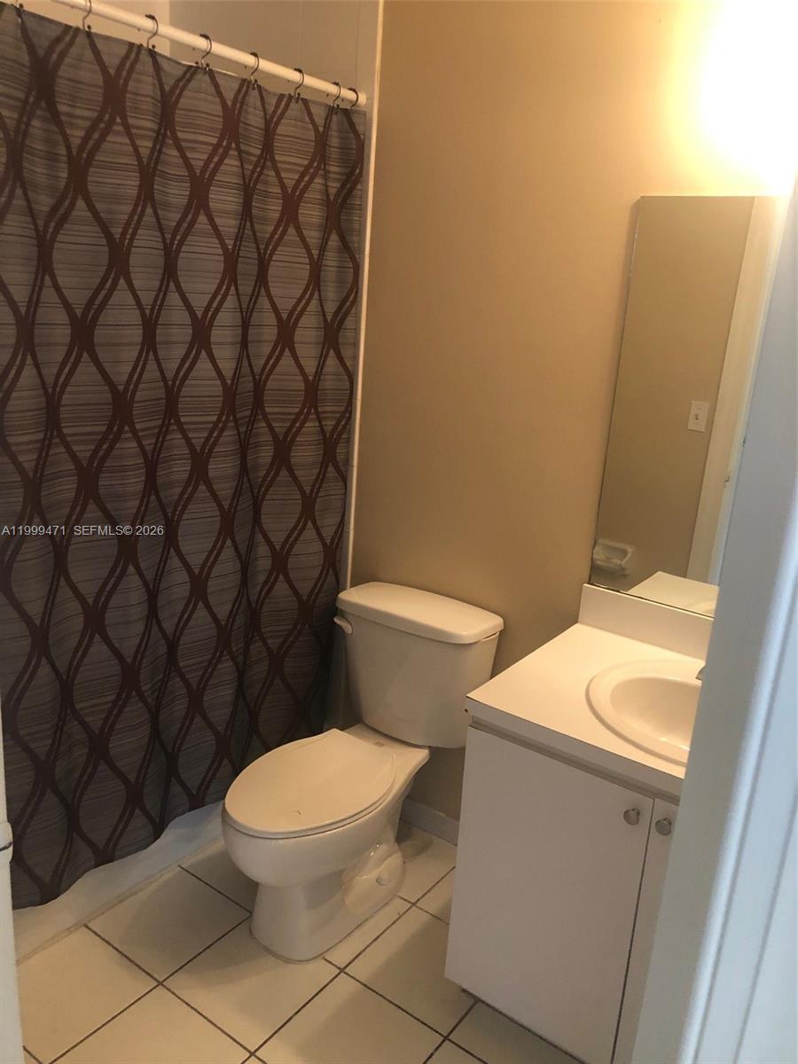12787 Southwest 257th Street, Unit 12787 Homestead, FL 33032 - Photo 4 of 5 a white toilet sitting next to a shower curtain