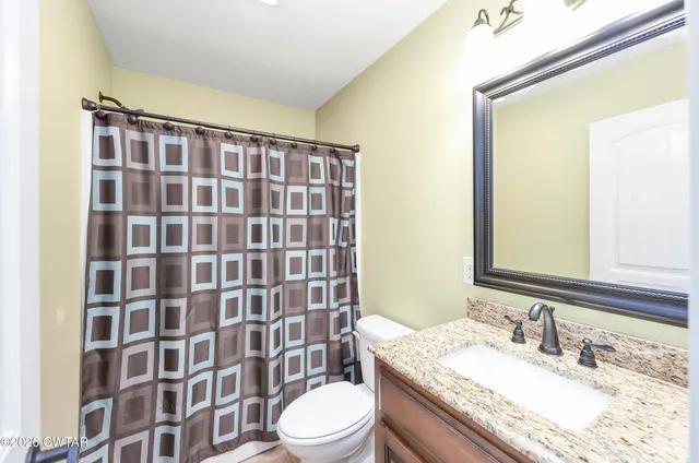 a bathroom with a granite countertop sink toilet a mirror and shower