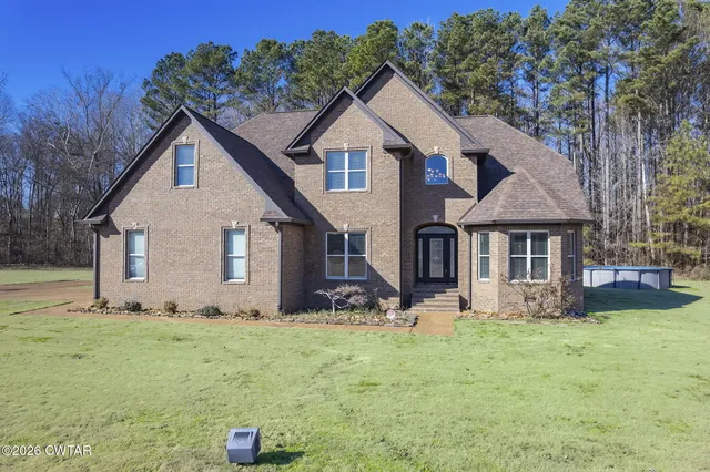 a front view of house with yard and trees in the background