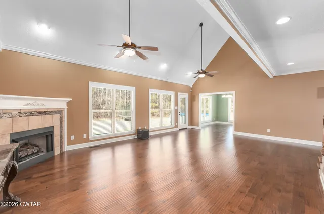 a view of an empty room with wooden floor fireplace and a window