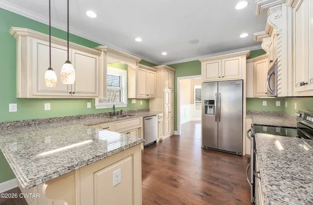 a large kitchen with stainless steel appliances granite countertop a refrigerator a oven and a wooden floors