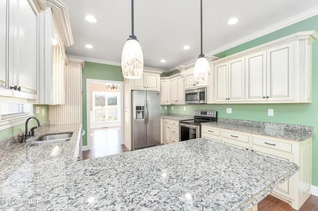a kitchen with stainless steel appliances granite countertop a sink refrigerator and cabinets