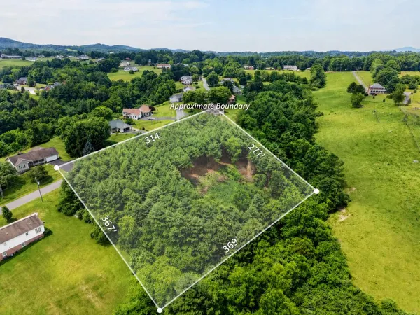 an aerial view of residential houses with outdoor space and trees all around