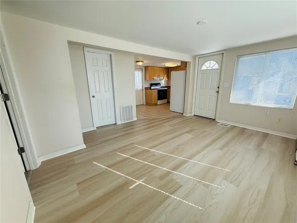 a view of an empty room with wooden floor and a window