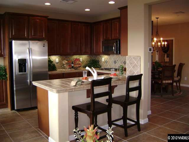 1920 A Wind Ranch Road, Unit A Reno, NV 89521 - Photo 1 of 4 a kitchen with a dining table chairs refrigerator and cabinets