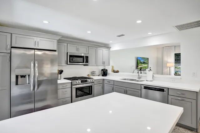 a kitchen with stainless steel appliances a sink stove refrigerator and cabinets