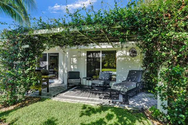 a view of a patio with table and chairs potted plants and large tree