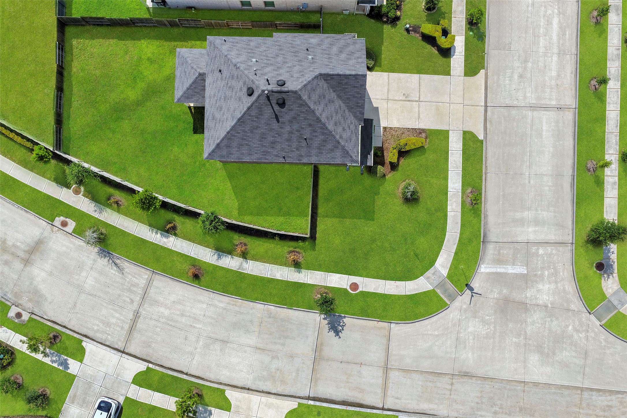 10603 Whitejacket Conroe, TX 77385 - Photo 42 of 42 This aerial photo showcases a modern home on a spacious corner lot with well-manicured lawns. The property is surrounded by a wooden fence and features a wide driveway leading to the house. The neighborhood has clean, wide streets and sidewalks, offering a tidy and inviting environment.