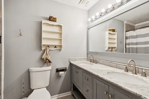 a bathroom with a granite countertop toilet sink and mirror