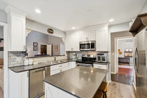a kitchen with stainless steel appliances granite countertop a sink a stove top oven a counter space and cabinets