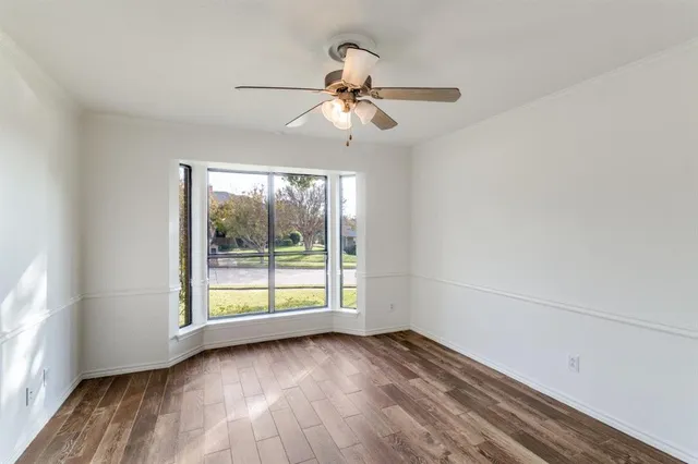 an empty room with wooden floor fan and windows