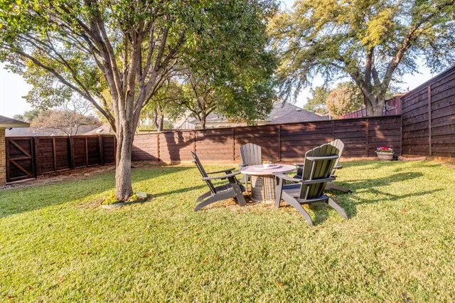 a view of a backyard with table and chairs and a large tree