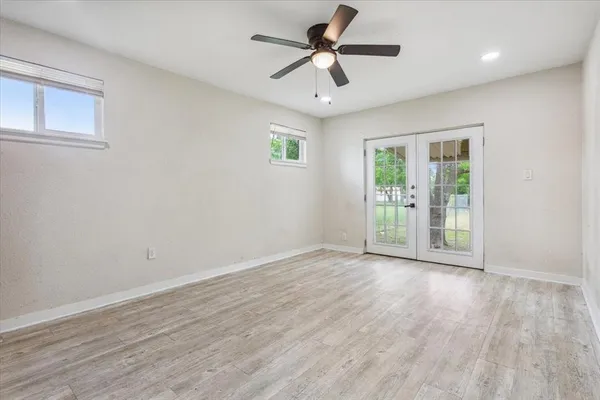 an empty room with wooden floor and windows