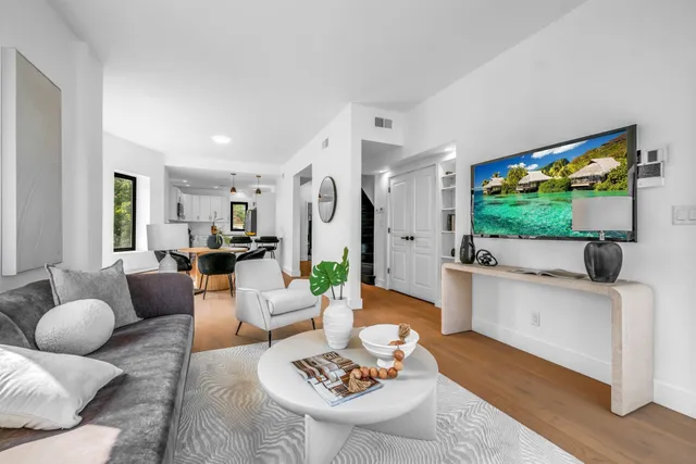 a kitchen with stainless steel appliances kitchen island granite countertop a refrigerator a stove a sink and white cabinets with wooden floor