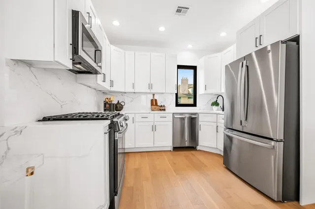 a kitchen with stainless steel appliances white cabinets and a stove top oven