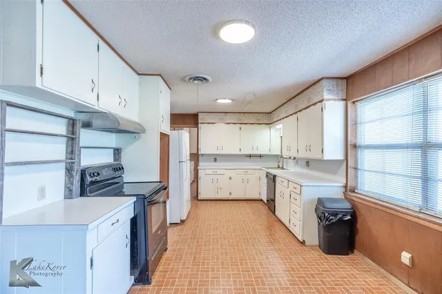 a kitchen with a sink stove top oven and white cabinets