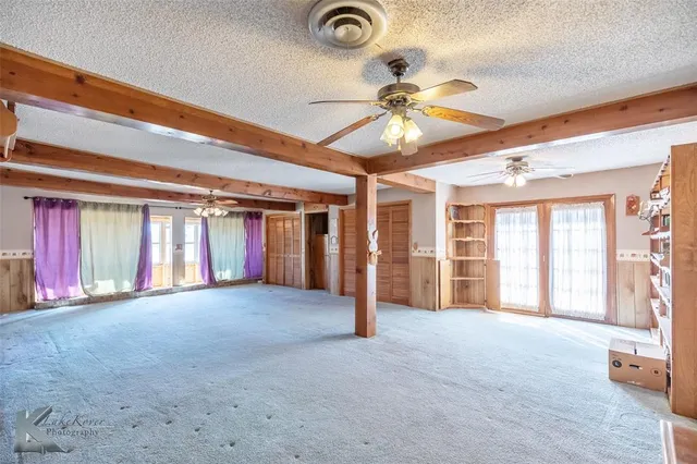 a view of an empty room with window and a ceiling fan