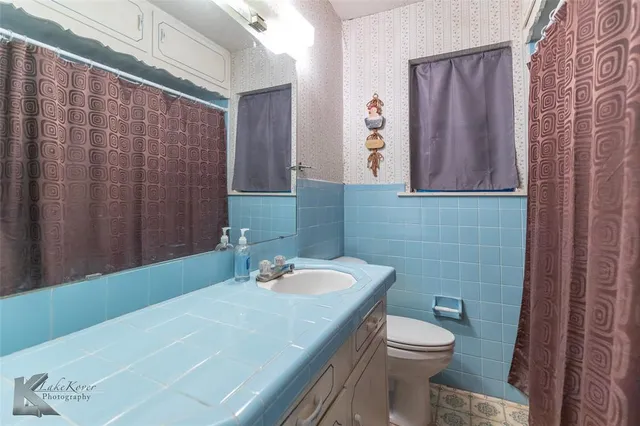 a bathroom with a sink a toilet and shower curtain