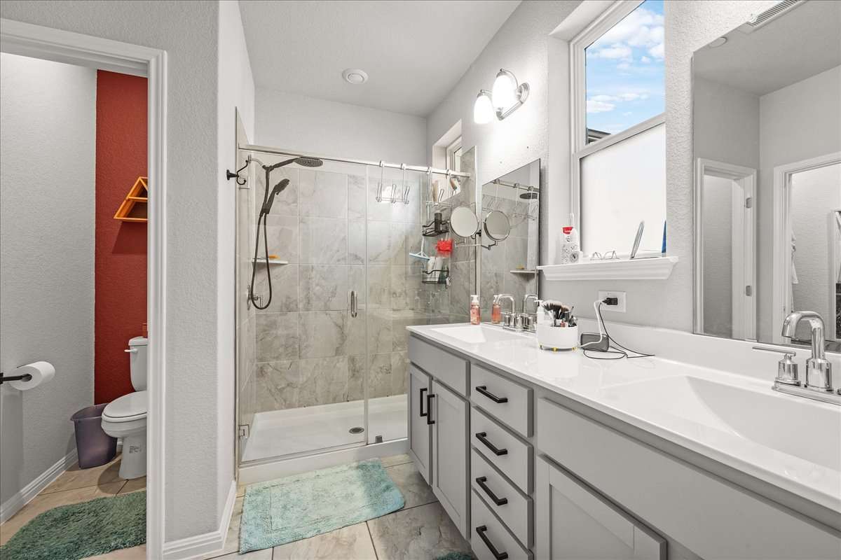 9015 Cattle Baron Path, Unit 1203 Austin, TX 78747 - Photo 15 of 23 Full bathroom featuring double vanity and a shower stall