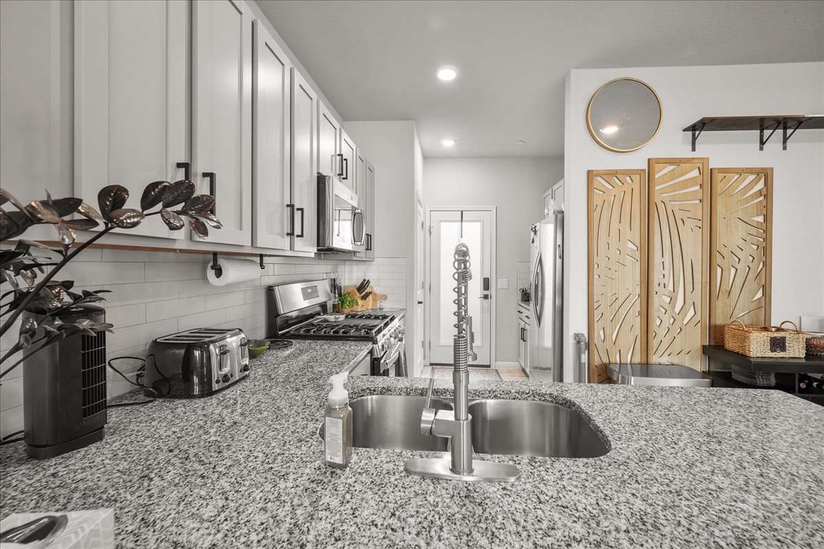 9015 Cattle Baron Path, Unit 1203 Austin, TX 78747 - Photo 5 of 23 Kitchen featuring stainless steel appliances, light stone countertops, backsplash, and recessed lighting