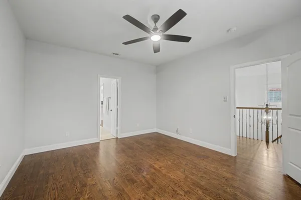 an empty room with wooden floor and ceiling fan