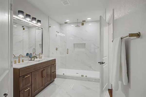a bathroom with a double vanity sink mirror and shower