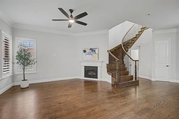 a view of a livingroom with wooden floor a ceiling fan and a window