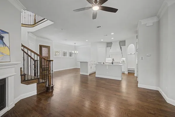 a view of an empty room and kitchen with wooden floor