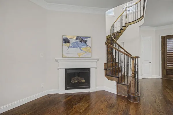 a view of an empty room with wooden floor fireplace and a window