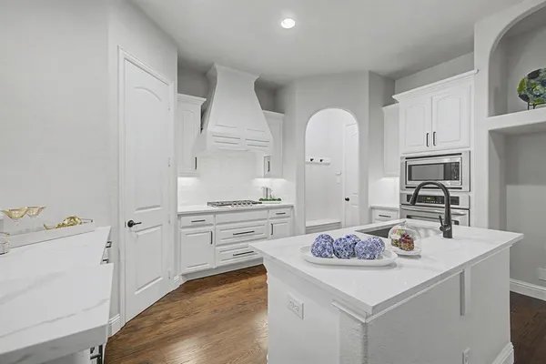 a kitchen with stainless steel appliances a stove a sink dishwasher and white cabinets with wooden floor